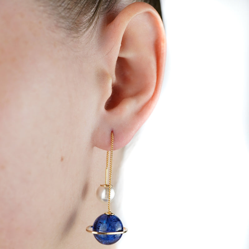 closeup darkblue planet earrings worn on ear by girl