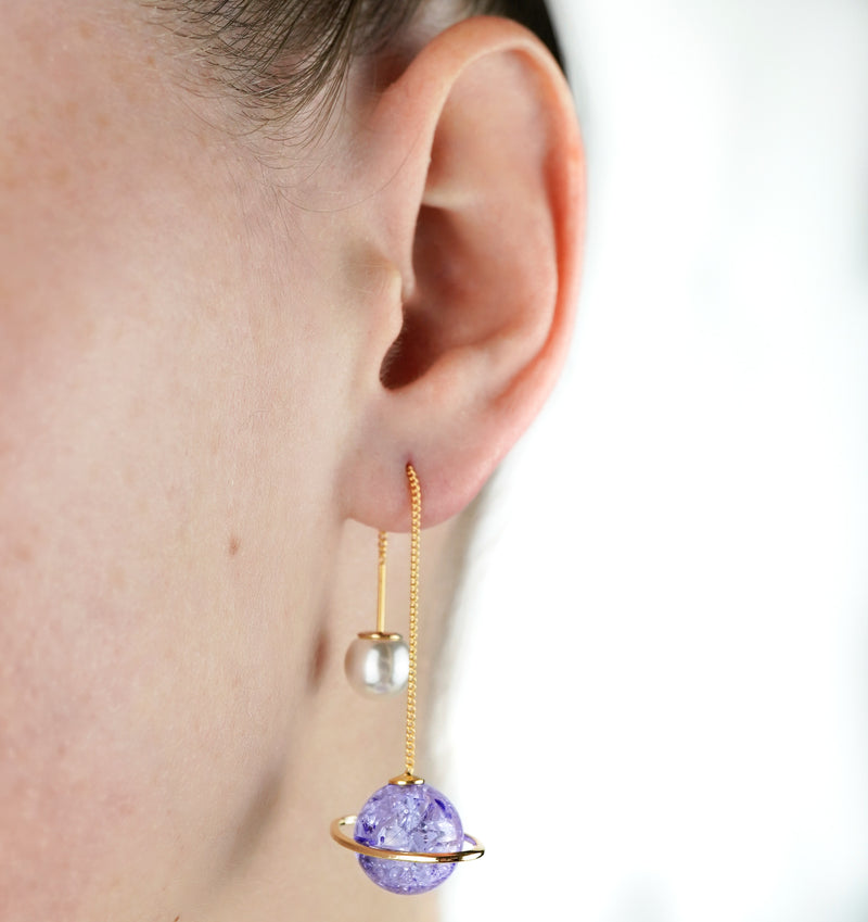 close up purple planet saturn pullthrough earrings with pearl worn by girl 